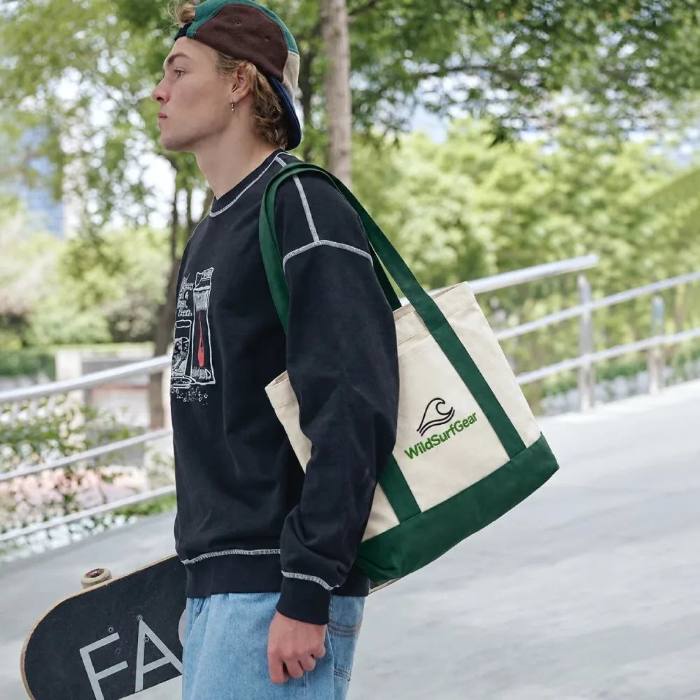 Man carrying WildSurfGear canvas tote bag with skateboard outdoors