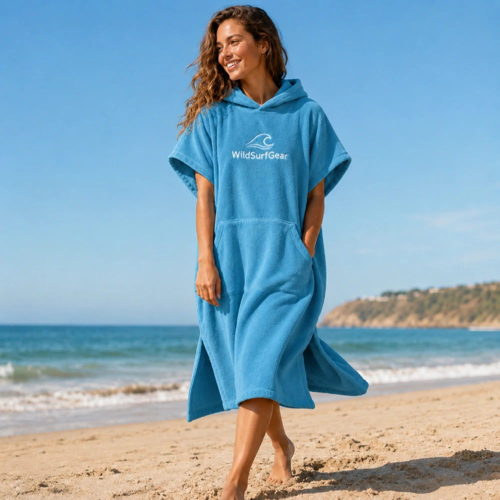 Woman wearing a blue 360GSM cotton surf poncho changing robe on the beach